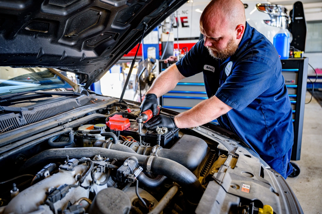 Auto technician inspecting vehicle in shop